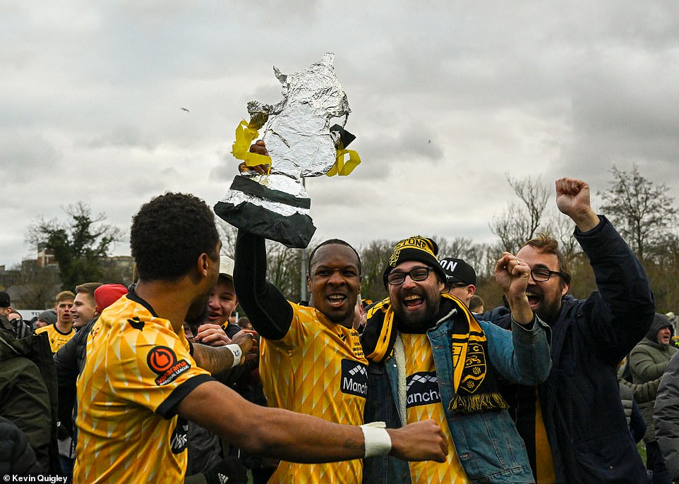 Players and supporters celebrated joyfully with the same DIY trophy after entering the field after the final whistle