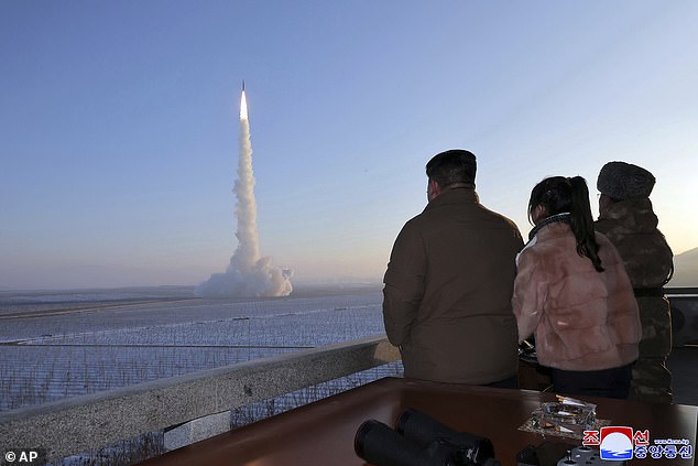 North Korean leader Kim Jong Un, his daughter and an official look at what appears to be an intercontinental ballistic missile being launched from a secret location in North Korea in a photo released in December