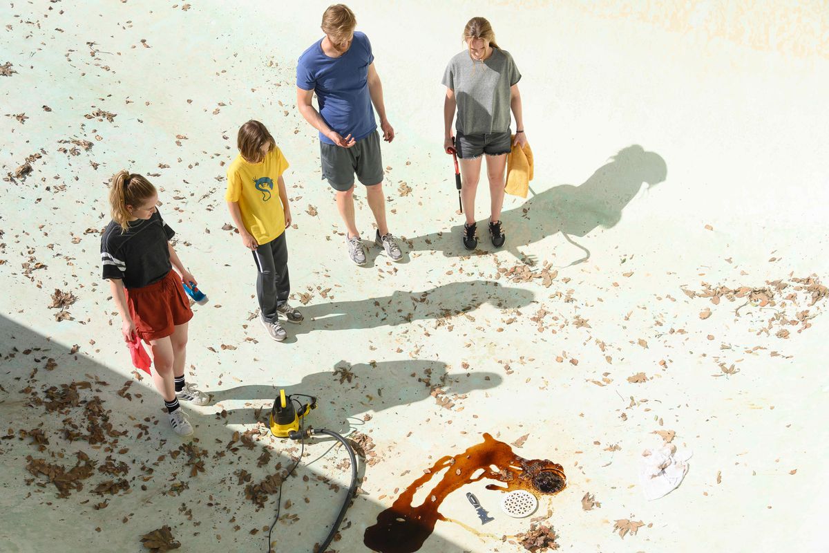 Amélie Hoeferle, Gavin Warren, Wyatt Russell and Kerry Condon stand in a pool surrounded by blood and dirt in Night Swim