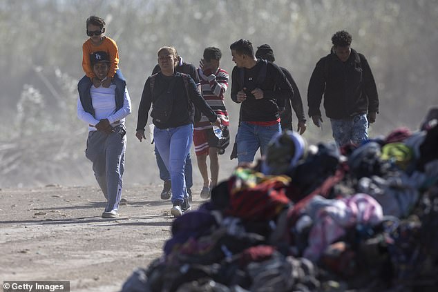 Immigrants from Venezuela walk past a pile of discarded migrant clothing after crossing the Rio Grande into the United States in Eagle Pass, Texas on January 8, 2024