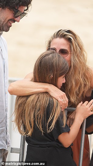 Elsa, ever the loving mother, hugged her daughter India Rose on the sand