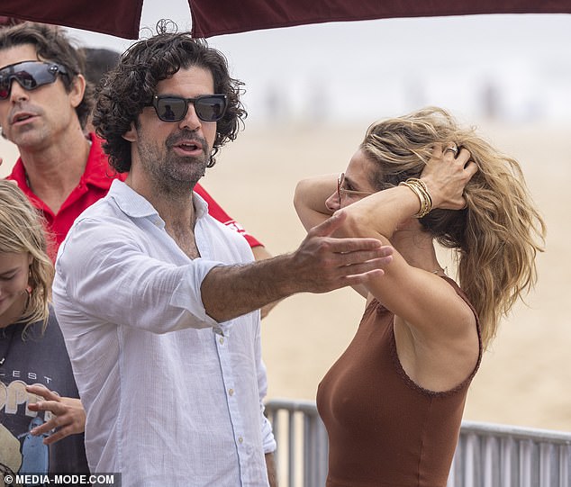 Elsa stroked her hair in the heat as the pair chatted on the beach