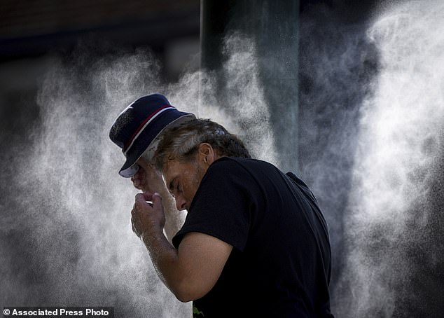 A man cools down at a temporary misting station deployed by the city in the Downtown Eastside due to a heat wave, in Vancouver, British Columbia, August 16, 2023