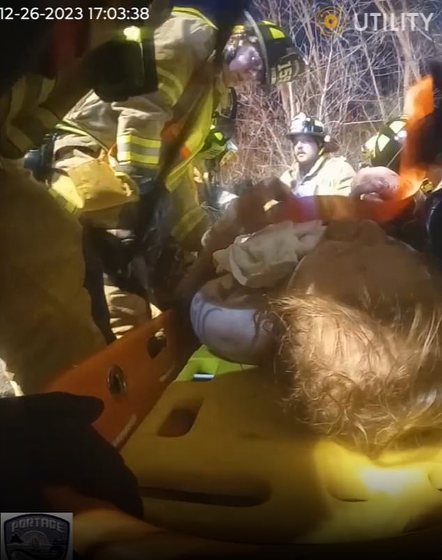 As it begins to get dark outside, they continue to try to free him - until they are finally able to cut him out with a saw and stretch him out from under the bridge.