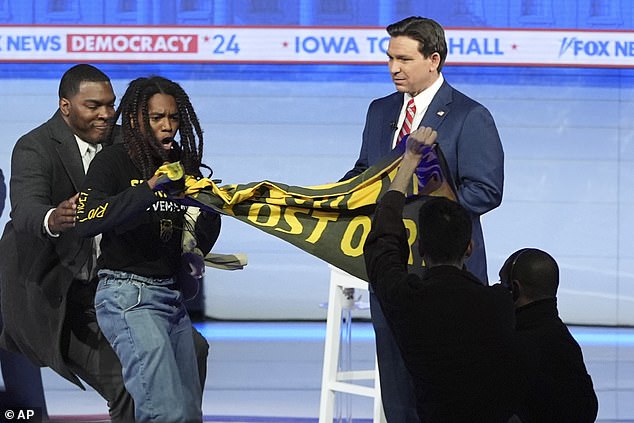 A security guard at the Fox News town hall deals with one of the protesters who tried to get on stage Tuesday night