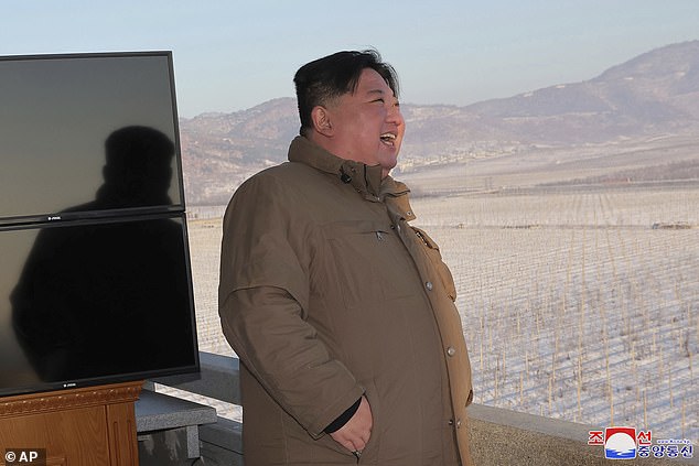 Kim watches a rocket launch during a test in December