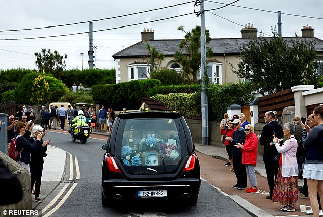 Pictured: Onlookers applaud as Sinead O'Connor's coffin passes her former home