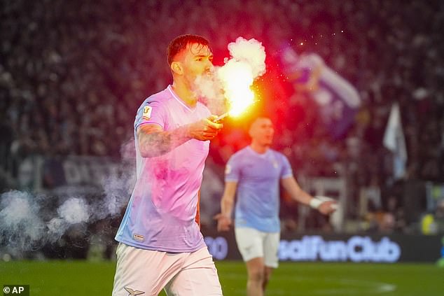 Lazio player Alessio Romagnoli holds a flare that was thrown onto the pitch during the match