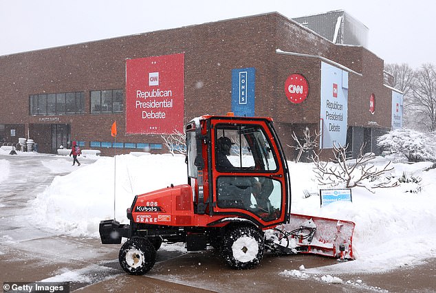 Drake University's Olmsted Center is pictured preparing Tuesday as a plow clears snow from the sidewalk after a winter storm passed through Des Moines days before the caucuses