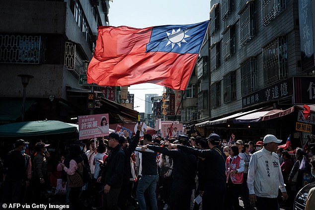 A supporter of the main opposition Kuomintang (KMT) party waves the national flag during a campaign rally