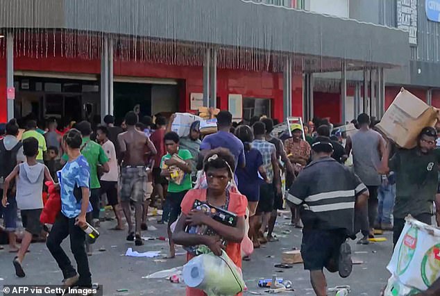 Looters in the capital rush into stores through broken windows and stuff stolen goods into cardboard boxes, shopping carts and plastic buckets