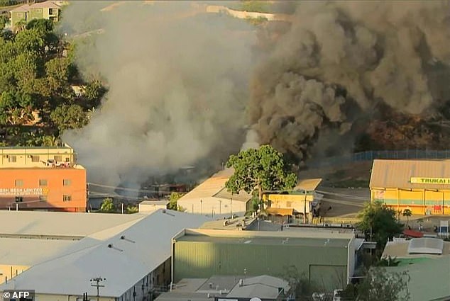 Smoke rises from a fire in a building in Port Moresby after riots broke out that left 15 people dead