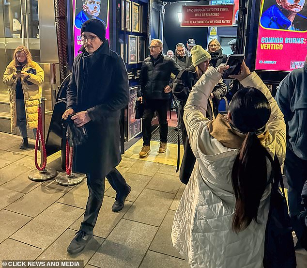 Caspar opted for a black jacket and matching scarf, which he combined with dark jeans and a black cap