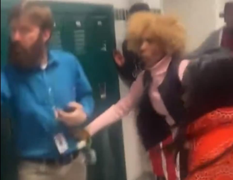 The shocked teacher grabs another staff member for support as the teenager is led away by another student