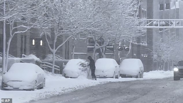 A person clears snow from his car during a snowstorm in Des Moines, Iowa on Tuesday, January 9, 2024