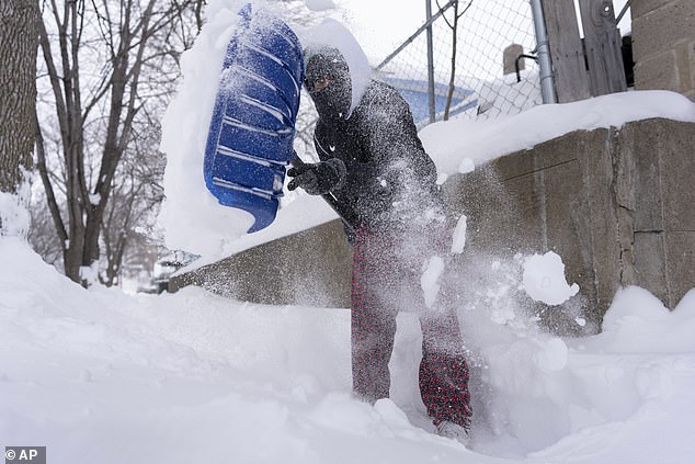 Giovanni Gonzalez clears his sidewalk in Sioux City, Iowa, during the snow on Friday