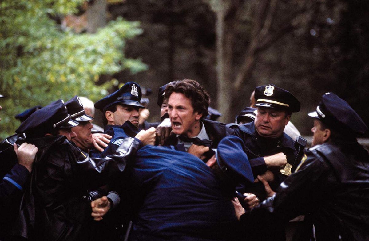 Sean Penn as Jimmy Markum is stopped by a group of police officers in Mystic River.