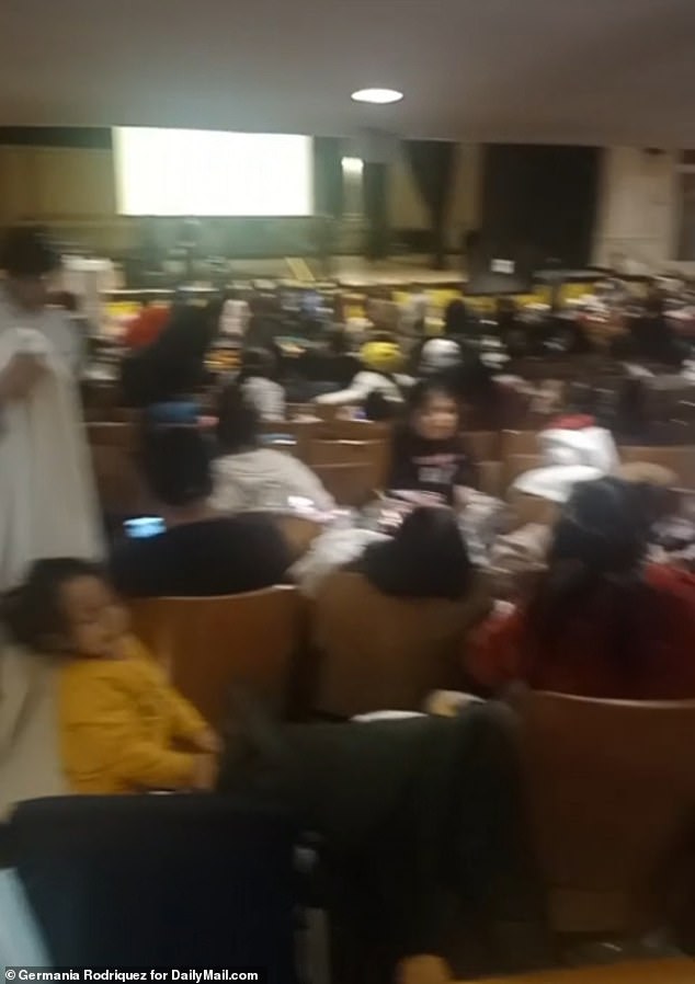 Shocking footage has shown hundreds of asylum seekers sleeping on the floor of a Brooklyn school auditorium after children were kicked out of classes so 2,000 migrants could move in.