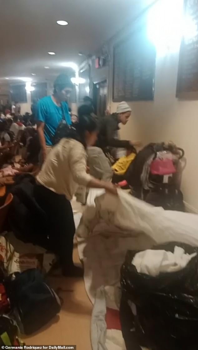 Clips obtained by DailyMail.com show the groups of migrants, young and old, taking up space in the school's main room, surrounded by their belongings