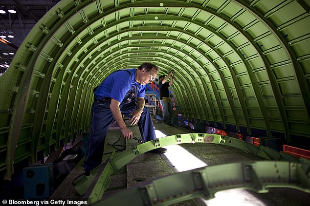 A worker applies sealer to the frame of a cargo door as the lower fuselage of a Boeing 737 is assembled at Spirit AeroSystems in Wichita, Kansas in a file photo