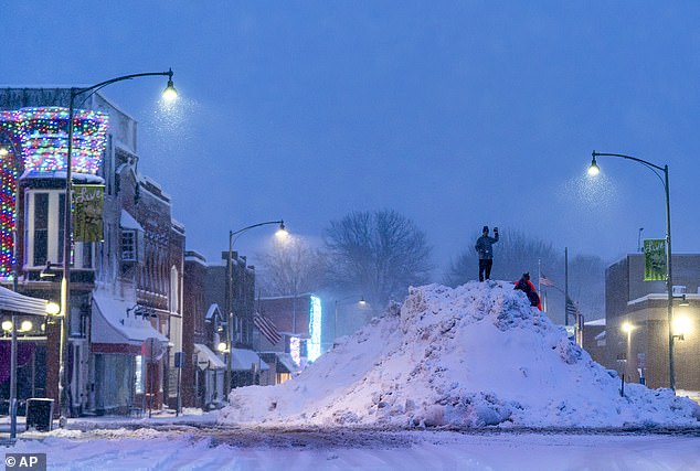 People stand on a large snow pile in Oskaloosa, Iowa on Tuesday