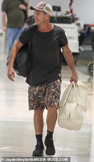 He completed his look with black socks and sneakers, and carried two duffel bags with carry-on luggage