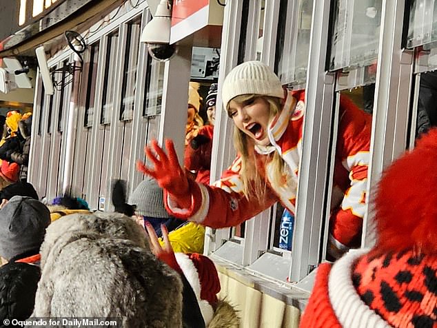 Travis' girlfriend Taylor Swift waves to fans in the frigid conditions at Arrowhead on Saturday