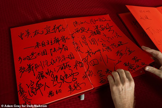 Chinese characters fill a red visitors' book kept in the house, recording guests' thoughts