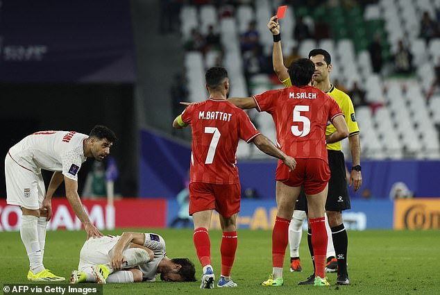 Referee Abdulrahman al-Jassim shows Palestinian defender Mohammed Saleh a red card, which was later withdrawn and replaced with yellow after review