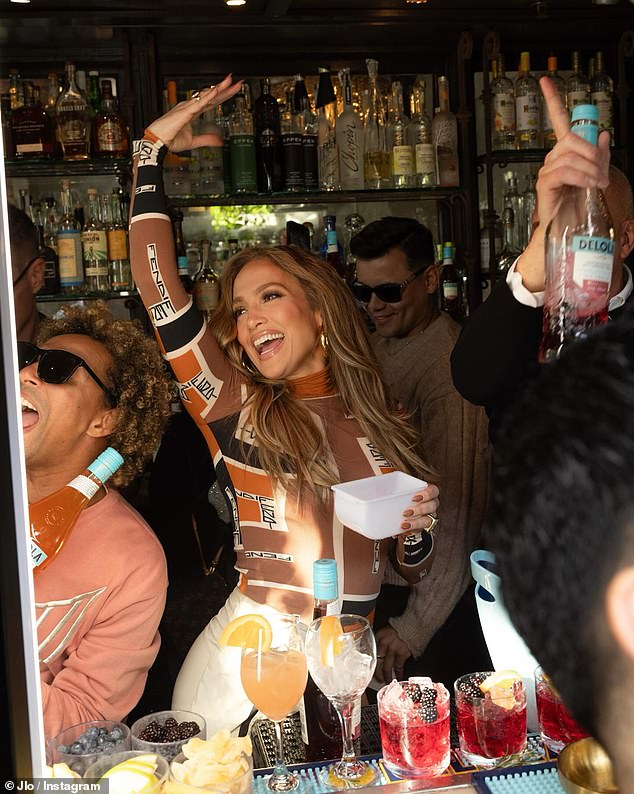 JLo was all smiles as she worked the bar in her stylish ensemble with pops of tan