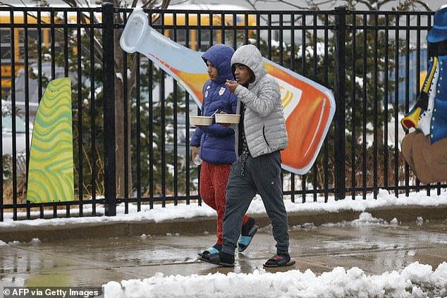 Migrants walk outside the migrant landing zone after receiving food during a winter storm on January 12, 2024 in Chicago, Illinois