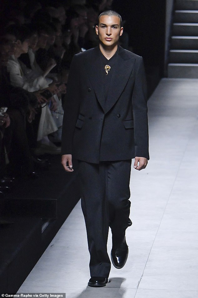 Nikko cut a chic figure as he walked the catwalk in a sleek black suit with a V-neck shirt underneath for the luxury Italian brand