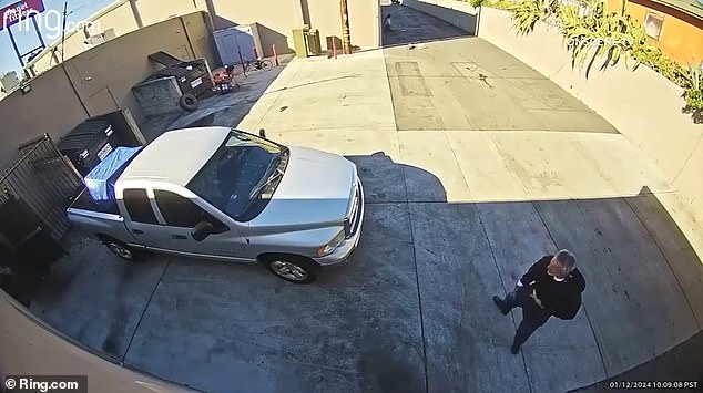 A man wearing a black hat on a bicycle rides in and approaches the man before clearly attacking him.  A fight ensues between the two.  Another man in a baseball cap watches the action