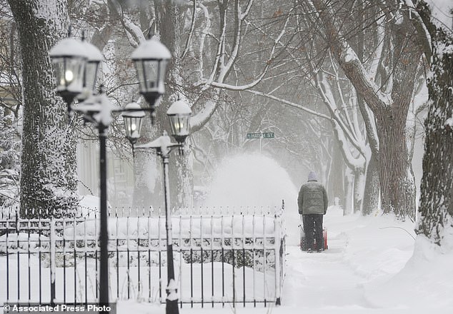 A man shovels snow along a sidewalk on State Street in St. Joseph, Michigan, on Monday