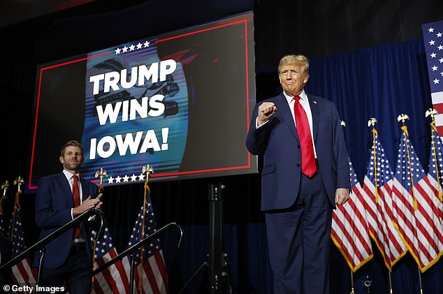 Former President Donald Trump raises his fist in the air after winning the Iowa Caucus on January 15, as son Eric looks on