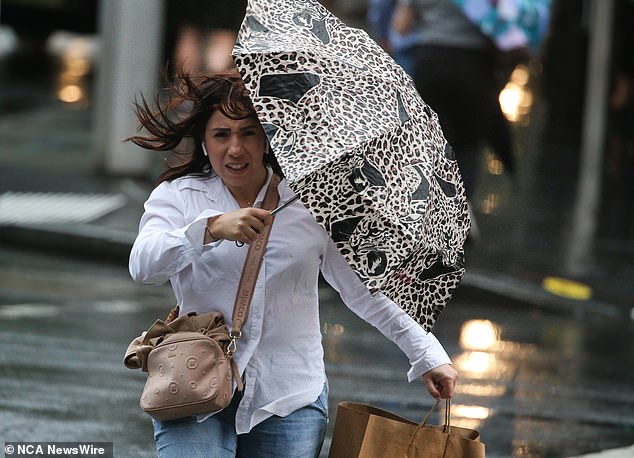 Australia's east coast will be hit by more heavy rain and storms.  The photo shows a woman battling wild weather in Sydney on Monday