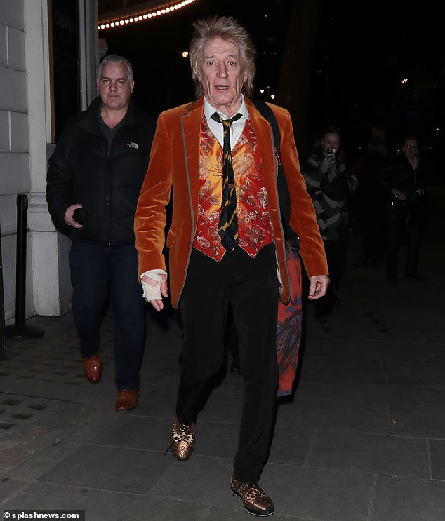 The musician's right hand was wrapped in a bandage, but he continued to show off his quirky style in a shiny orange vest decorated with floral embroidery