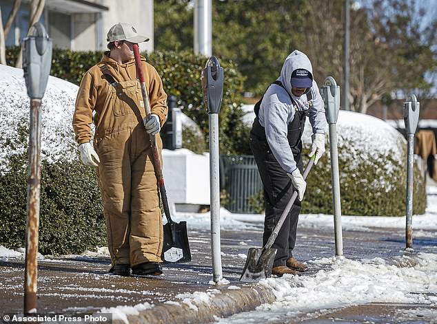 Florence Street Department workers shovel snow from a sidewalk near City Hall in downtown Florence, Alabama, on Tuesday