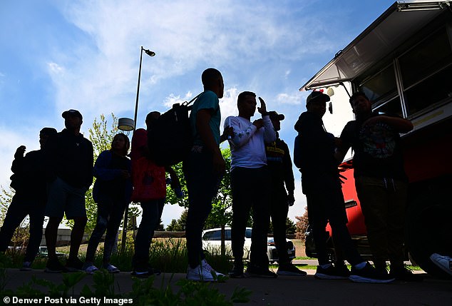 Venezuelan migrants wait in line for food from a food truck at a migrant processing center in Denver, Colorado on May 9, 2023