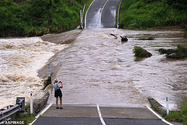 The ex-tropical cyclone brought severe wet weather that devastated dozens of communities with thunderstorms and heavy rainfall, flooding several areas (photo, floodwaters on a Queensland road)