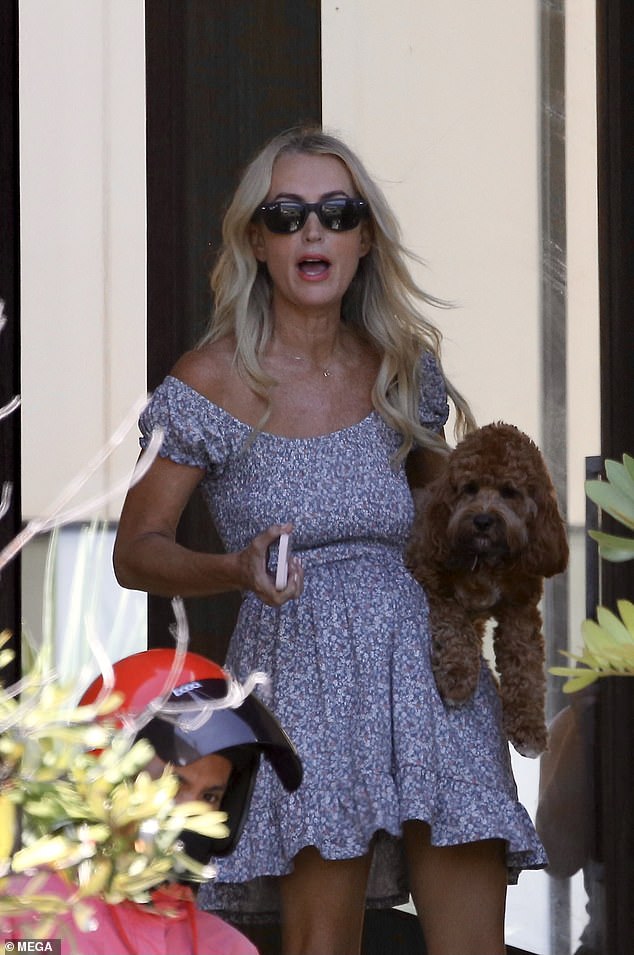 Jackie wore a mini floral dress and dark sunglasses as she held her dog and spoke to the delivery person