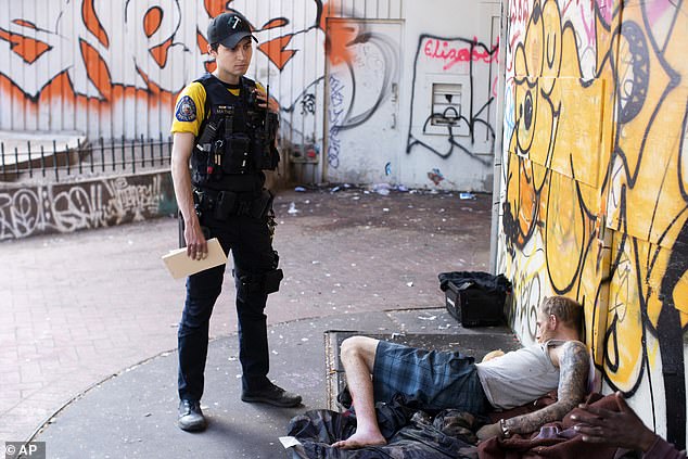 Officer Donny Mathew of the Portland Police Bureau's bicycle squad stands next to a person who appears to be unconscious in May 2023