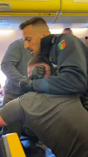 This is the shocking moment a holidaymaker was left in a standoff and forcibly marched off a Ryanair flight by police today after a flight from Luton to Lanzarote had to be diverted to Portugal due to his behaviour.