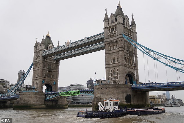 Activists from Extinction Rebellion hang from hanging ropes next to a giant banner reading 'End fossil fuels now' as they protest on Tower Bridge in east London, which is closed to traffic.  Date of photo: Friday April 8, 2022