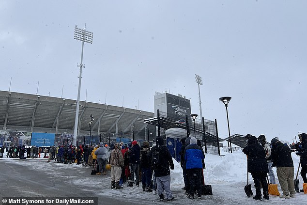 Hundreds of Bills fans line up at Highmark Stadium with shovels in their hands on a snowy Friday