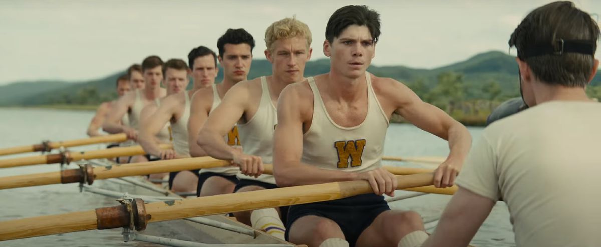 A boat full of men rows across a lake.