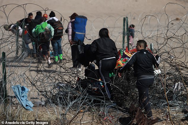 Migrants are pictured Wednesday walking through a barbed wire fence to get from Mexico to the United States, near Ciudad Juarez