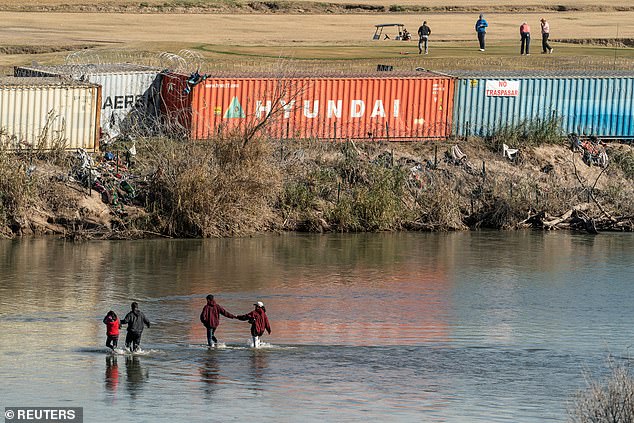 A group of migrants cross the Rio Grande near Eagle Pass, Texas, on Thursday as golfers play a round