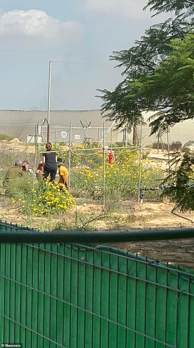 Nasreen Yussef seen with the four Hamas terrorists she captured who were being held in the backyard of her home in Moshav Y'ated.  In the photo she and her husband give the terrorists water and behind them – the white greenhouses – the other terrorists hid