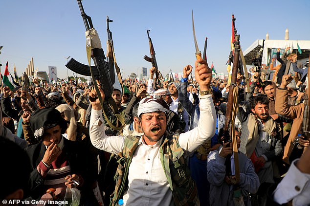 Houthi fighters brandish their weapons during a protest after attacks by US and British forces